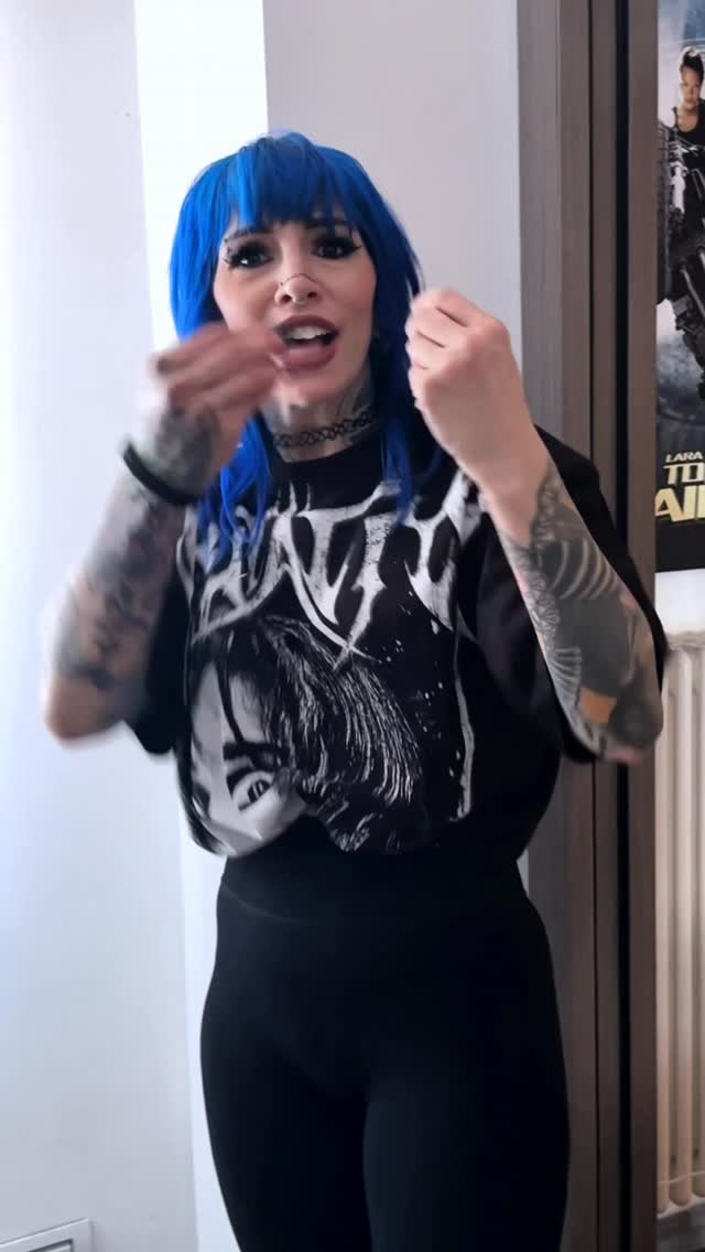 Person wearing black graphic t-shirt displaying full sleeve tattoos in black ink on both arms.