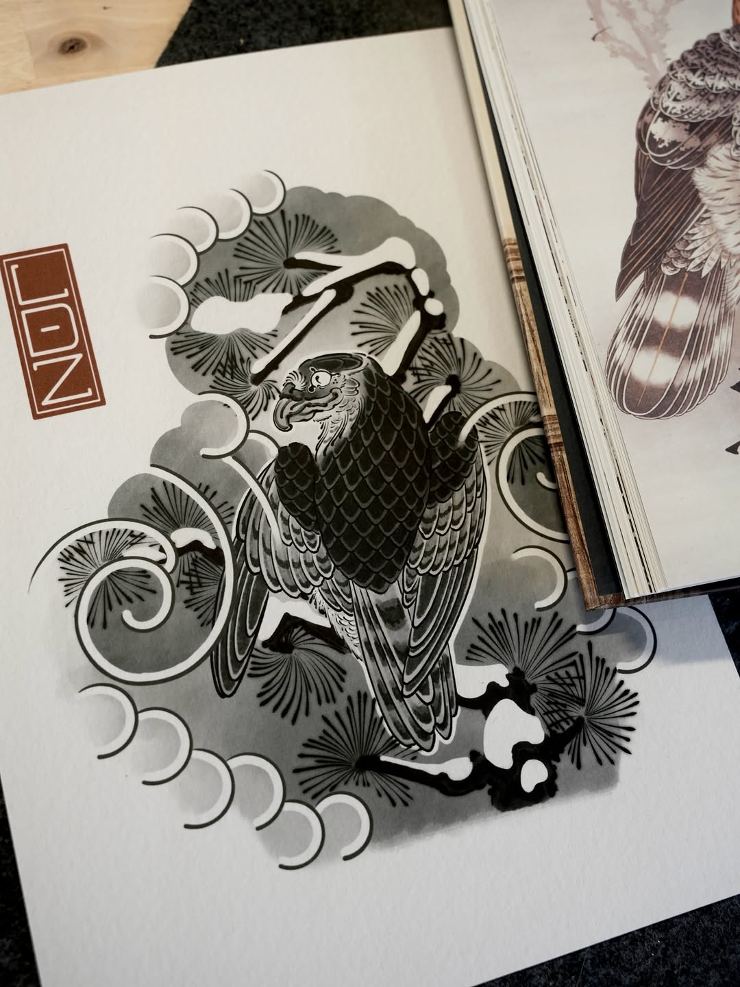 Detailed eagle tattoo design with intricate feather work, crescent moons, and ornamental flourishes rendered in black ink on white paper.