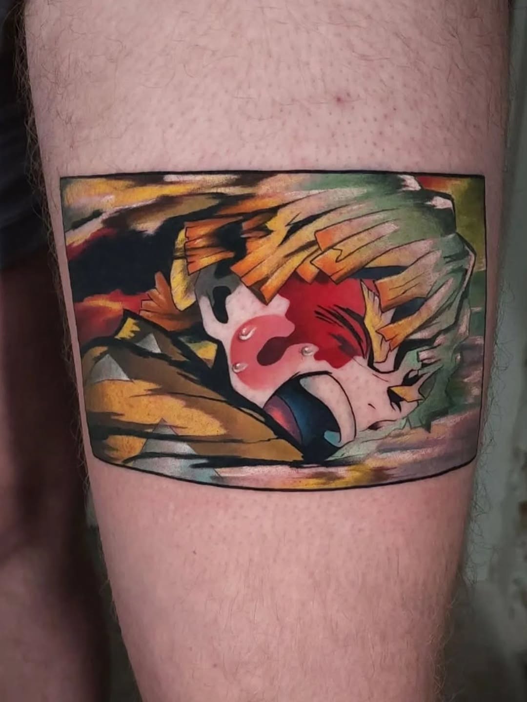 Colorful tattoo on upper arm featuring a red and white masked character with orange and black wing details against a green background.