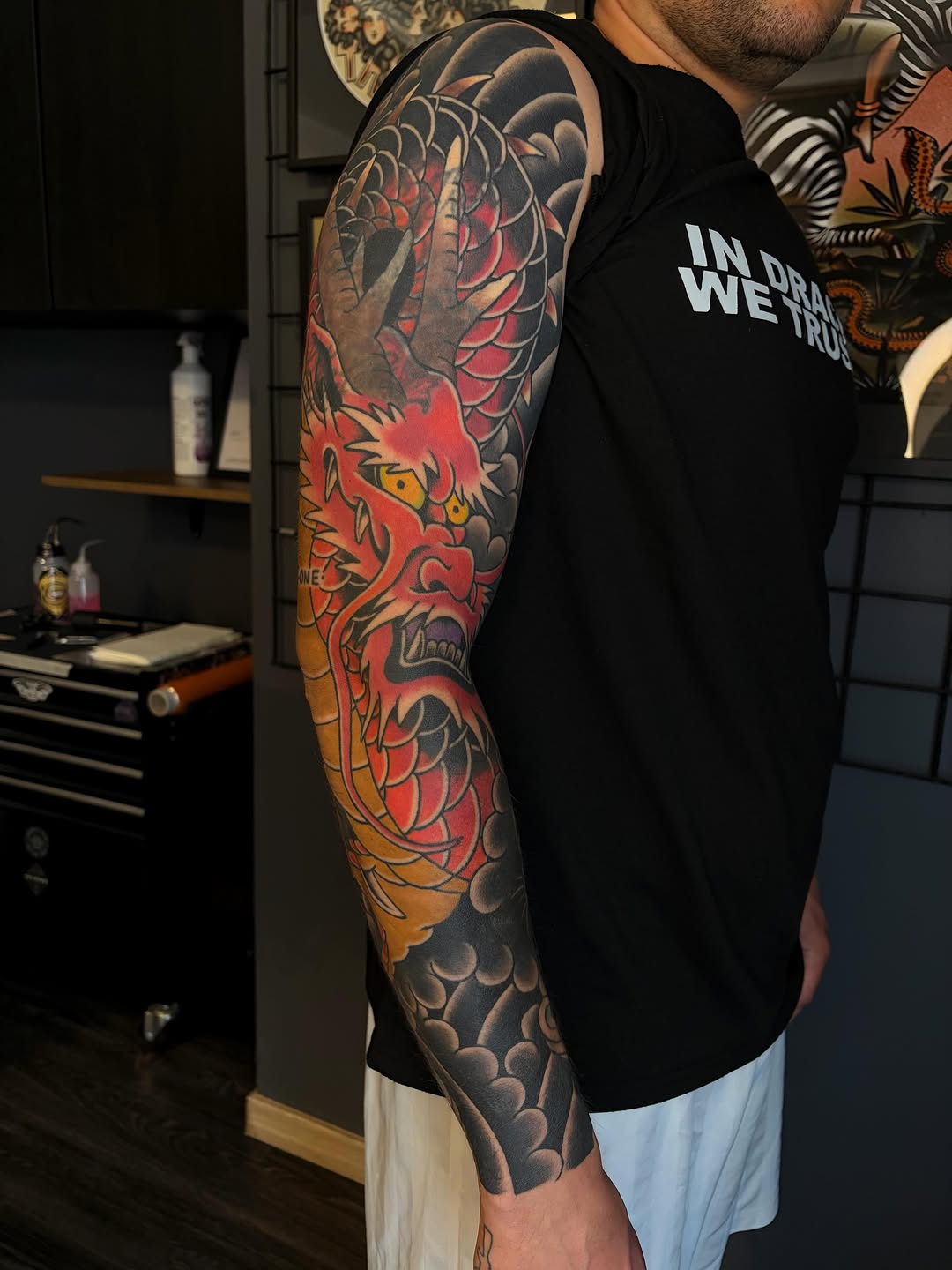 Colorful full-length arm sleeve tattoo featuring a red demon mask with gold eyes, dragon scales, and ornamental details in red, orange, yellow, and black.