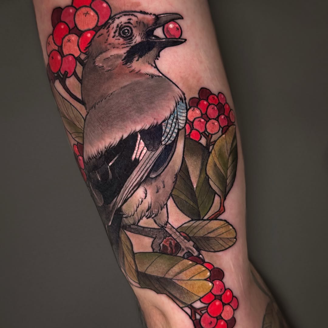Bird with brown and tan plumage perched among branches with red berries and green leaves, tattooed on the upper leg in red, brown, and gold tones.