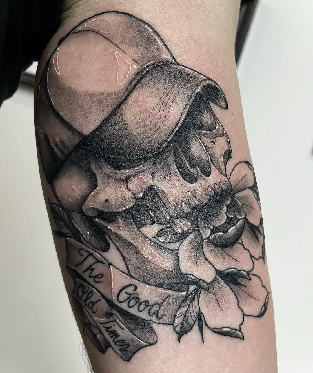 Skull with floral elements and script text reading "Good Times" on the upper arm, rendered in grayscale shading.