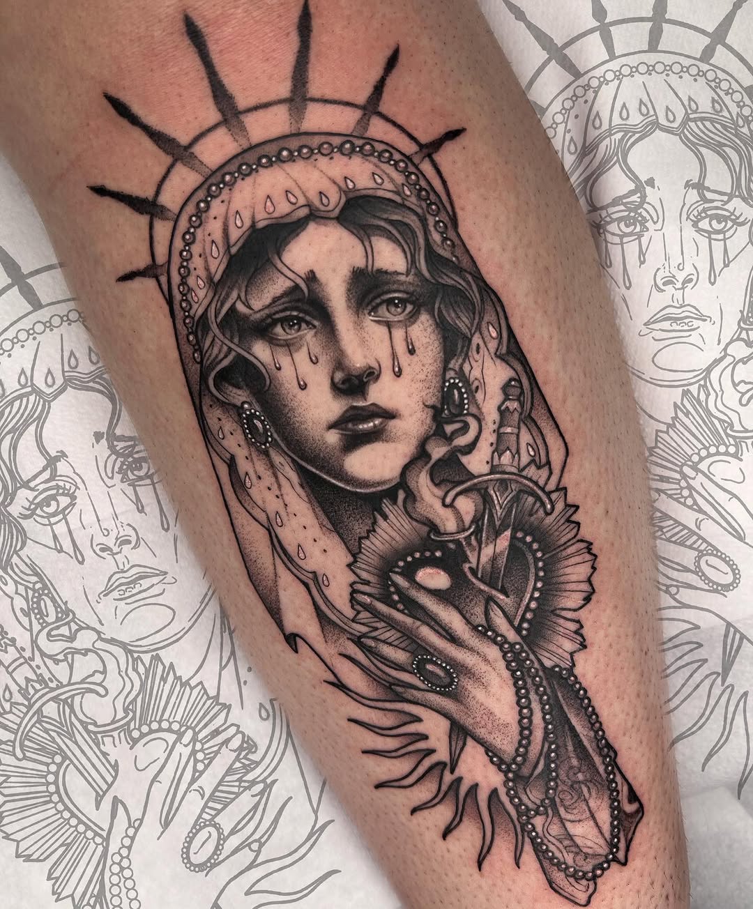 Tattoo on thigh featuring a crying face with a radiating halo and ornate headpiece, holding a decorative butterfly, rendered in black and grey ink.