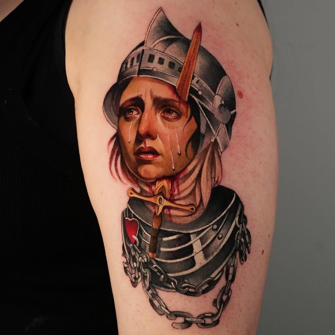 Medieval warrior with pointed helmet and red feather, wearing metal armor and chains, with tears on face, tattooed on upper arm in color.