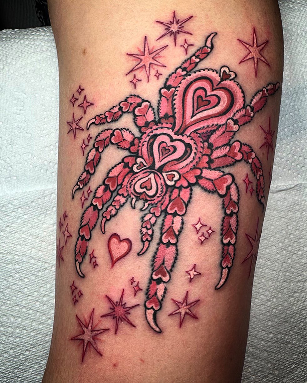 Pink and red heart-shaped design with leaf and vine motifs adorned with smaller hearts and stars, tattooed on the upper leg.
