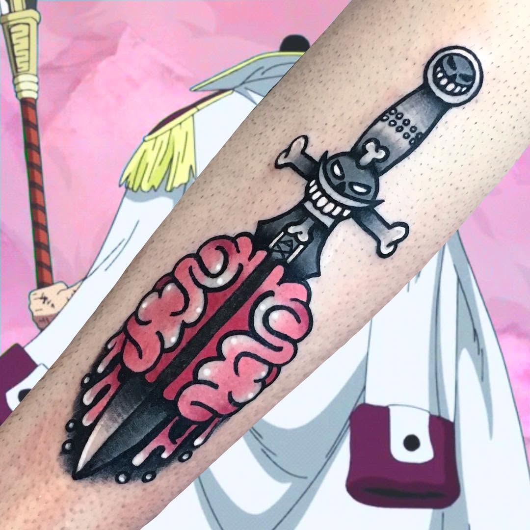 Tattoo on forearm featuring a black skeletal sword with pink ornamental scrollwork, topped with a grinning skull character, displayed against colorful background illustrations.