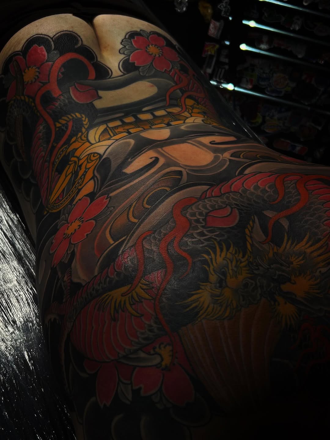 Vibrant leg tattoo featuring red flowers, orange and black ornamental patterns, and decorative scrollwork covering the thigh and calf area.