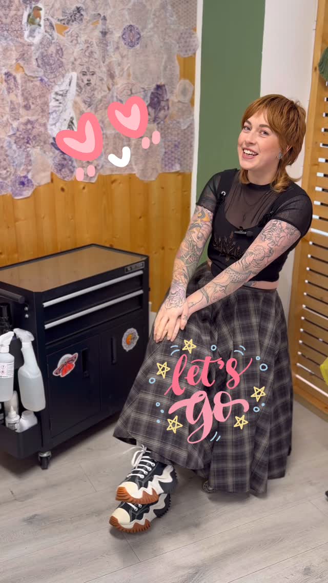 Tattooed woman displaying full sleeve tattoos on both arms featuring various colorful designs including flowers, animals, and abstract elements.