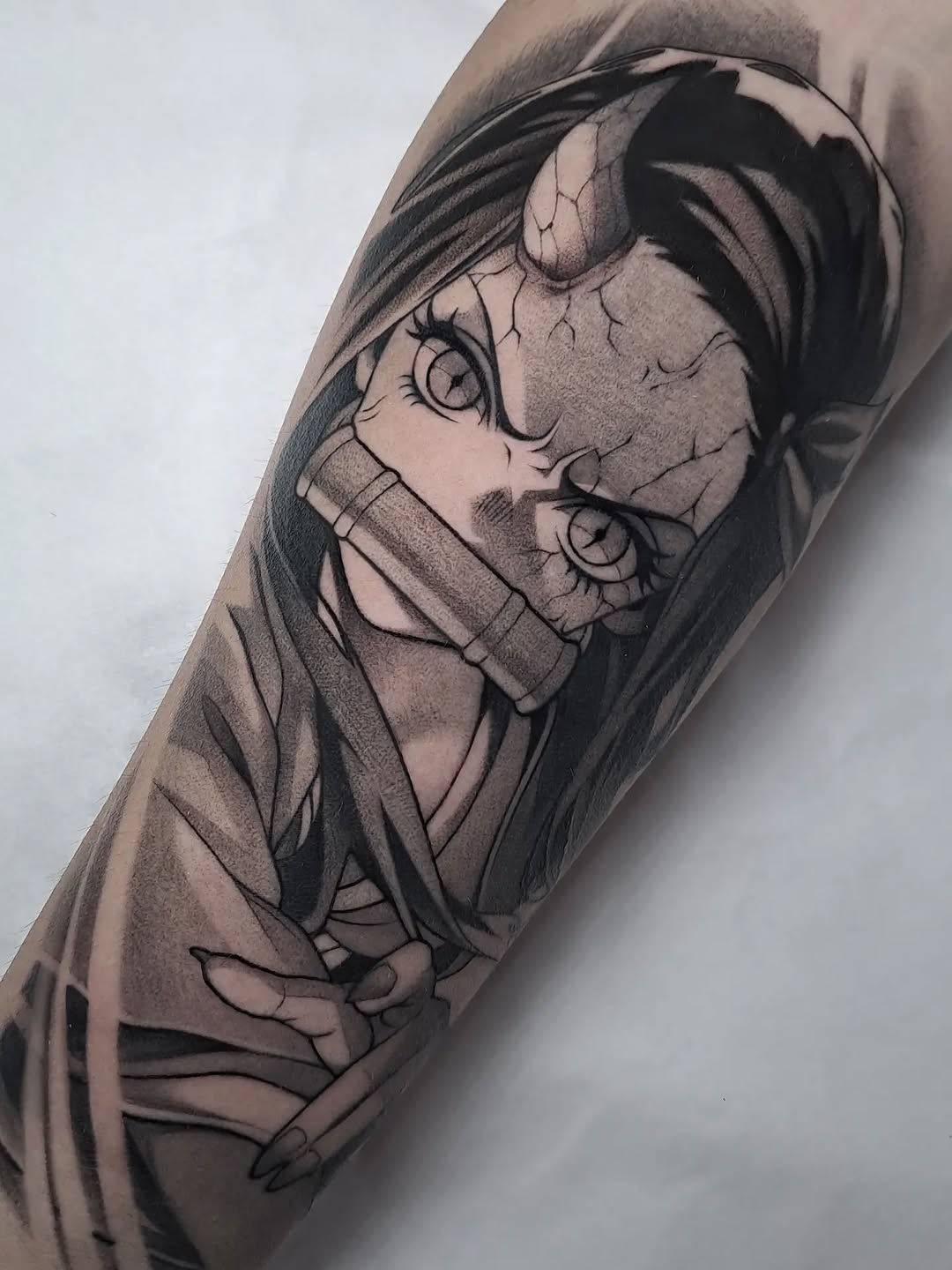 Tattoo on forearm depicting a character with closed eyes, headwrap, and detailed facial features in black and gray ink.