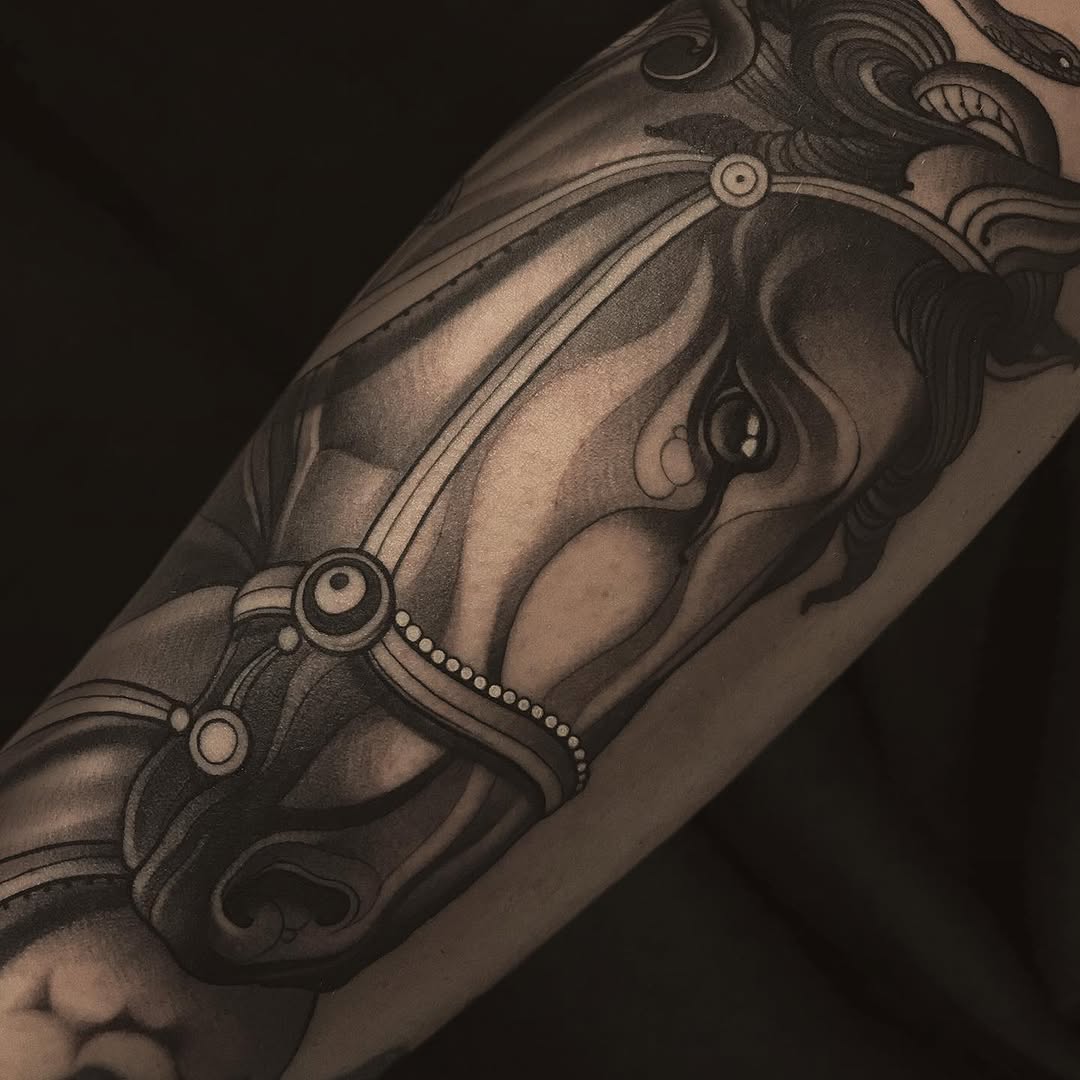 Ornate leg tattoo featuring a crowned face with decorative scrollwork, circular jeweled ornaments, and detailed shading in black and grey ink.