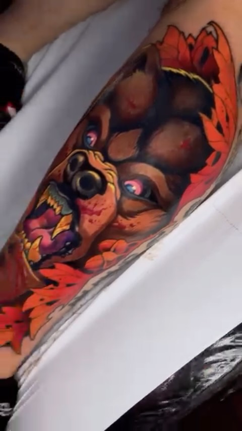 Vibrant red and orange fox tattoo on the forearm featuring detailed facial features and decorative leaf or fire-like patterns surrounding the design.