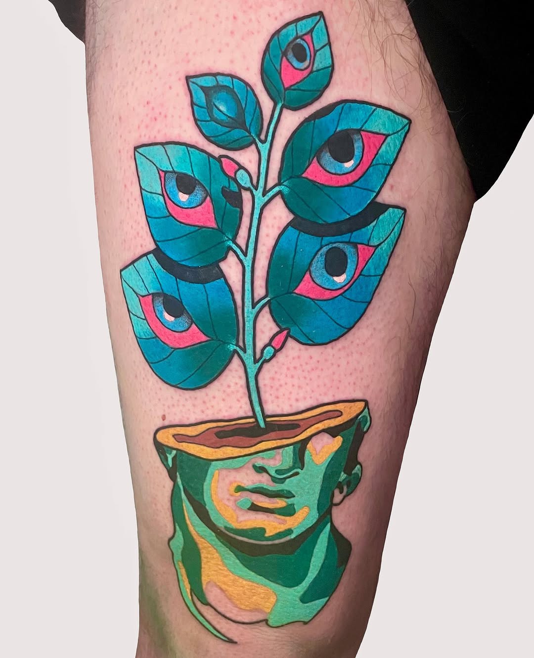 Colorful leg tattoo featuring a potted head with a plant growing from it, adorned with teal leaves and pink eyes, rendered in vibrant blues, greens, and yellows.