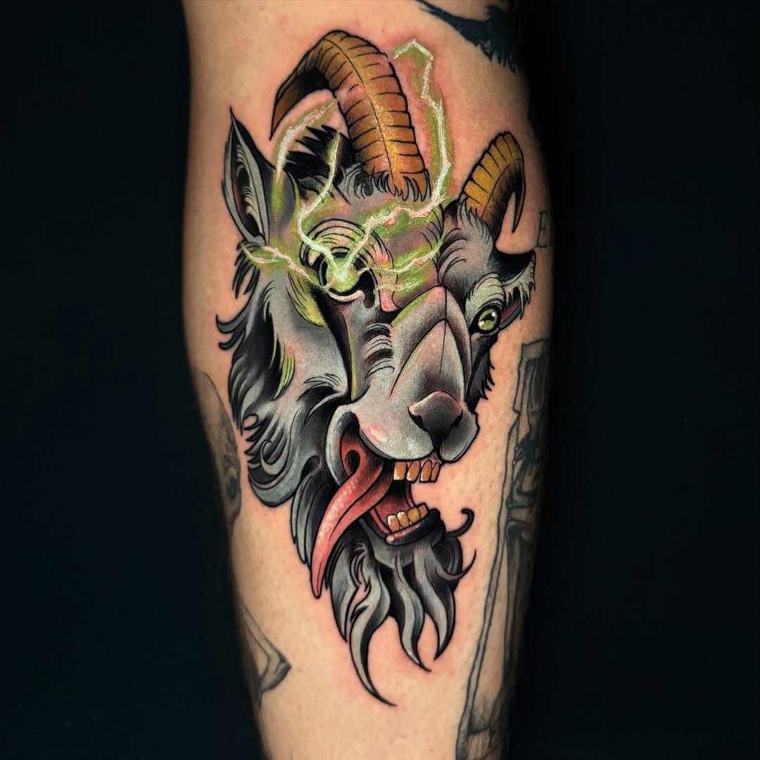 Demon head tattoo with curved horns, green glowing outline, red tongue, and dark beard on upper leg, featuring orange and gray tones.