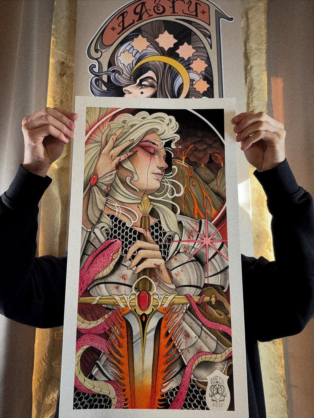Tattoo design featuring a pale-skinned figure with flowing blonde hair, golden halo, and ornate clothing in red, gold, and pink tones, displayed as a portfolio print.