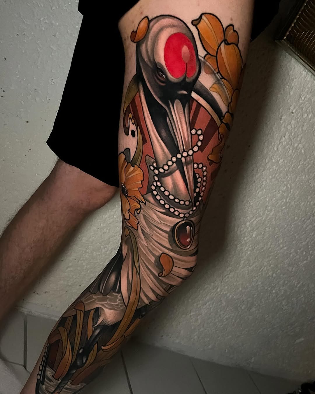 Full-leg tattoo sleeve featuring a figure with a large red circular face, pearl necklaces, orange butterflies, and ornate designs in red, orange, and black tones.