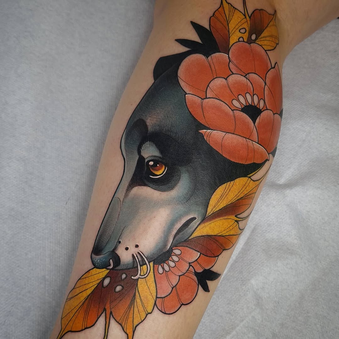 Greyscale dog head with golden eye surrounded by red and yellow flowers with black leaf details on an inner arm.