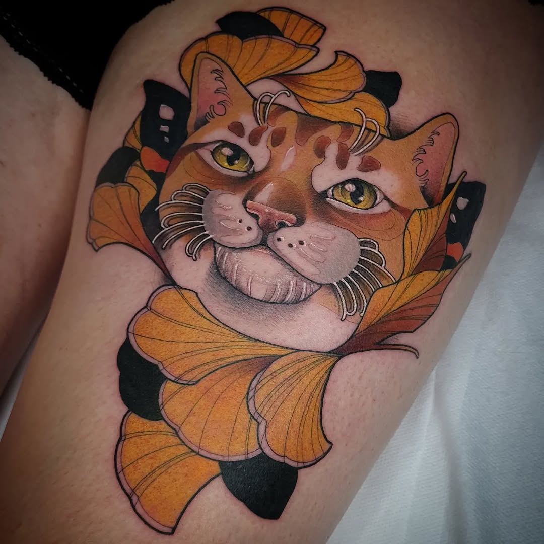 Orange and black cat face with yellow eyes and whiskers surrounded by butterfly wings on upper leg.