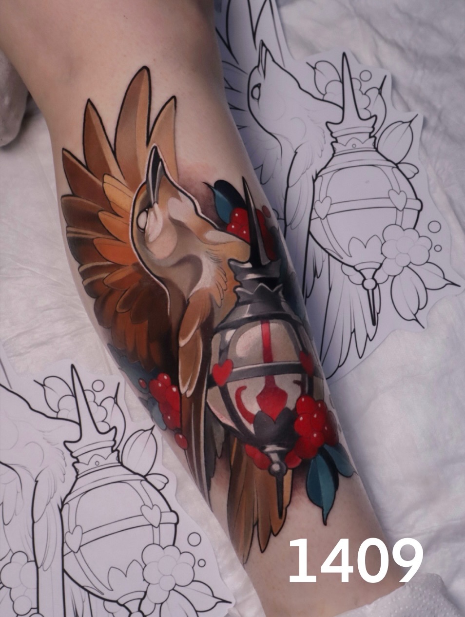 Colorful tattoo on forearm featuring a winged fox head with brown and orange tones, red berries, and black accents, displayed alongside sketch designs.