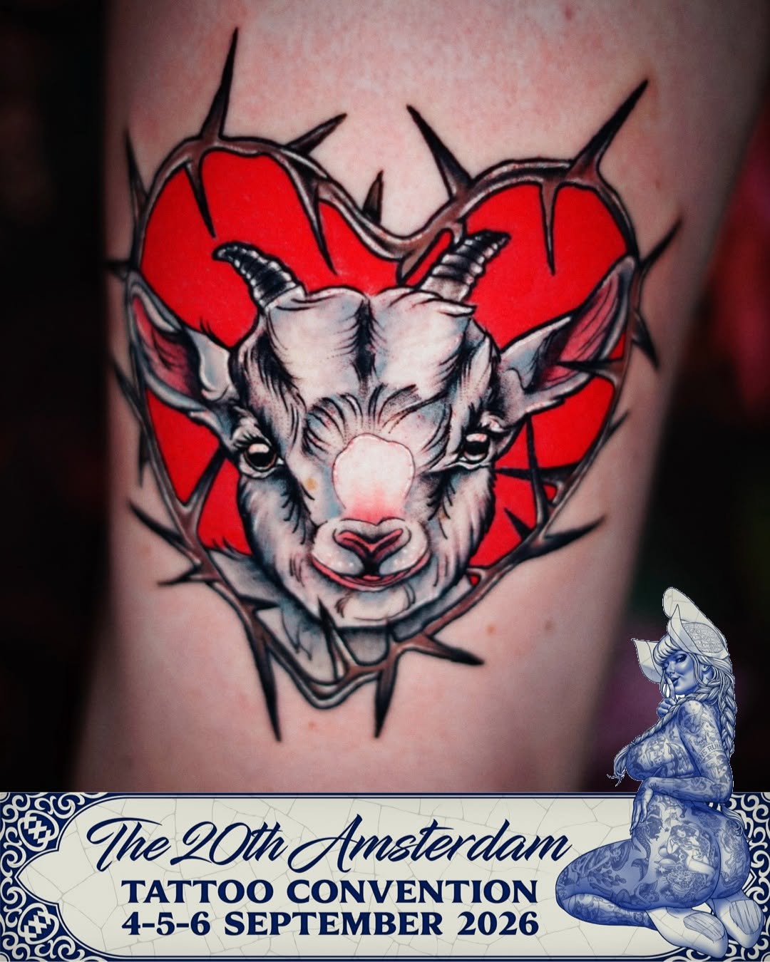 Goat head with curved horns and red heart-shaped background with black spikes on upper arm or shoulder.