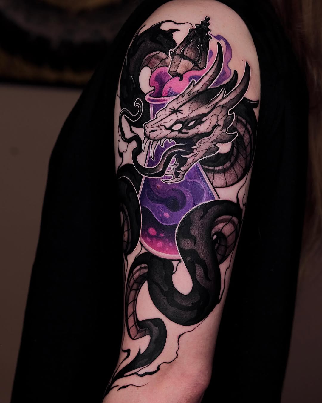 Colorful shoulder and arm tattoo featuring a demon mask with purple and pink accents, flowing black serpentine elements, and a bat in the upper design.