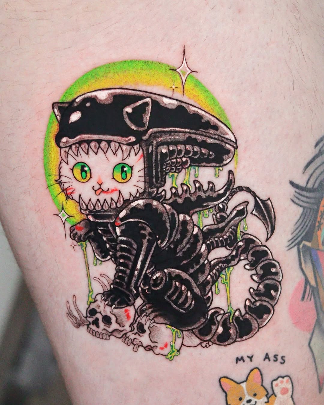 Colorful cat with sharp teeth emerging from biomechanical alien xenomorph creature with green and yellow gradient background on upper arm.