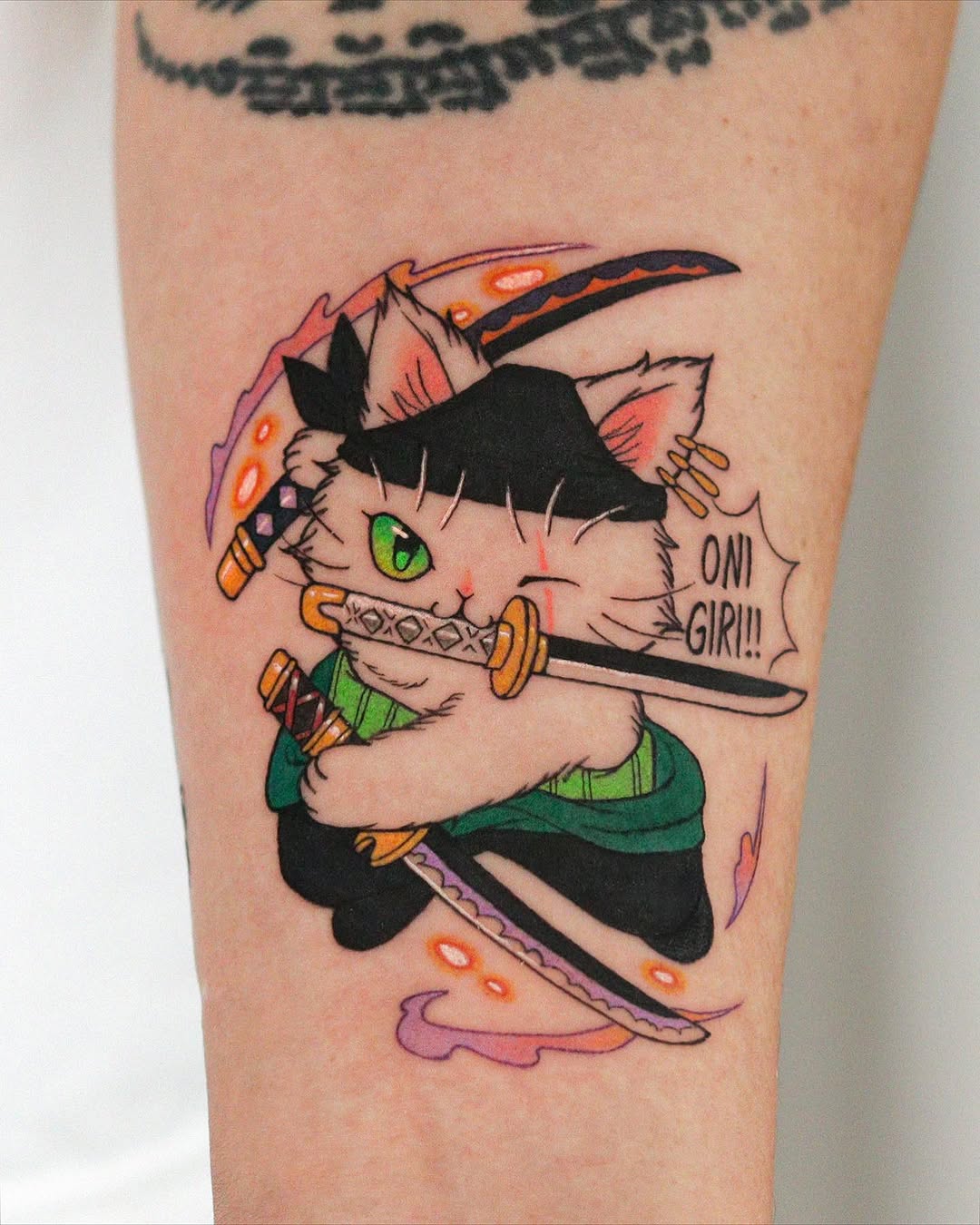 Colorful cat character tattoo on upper arm wearing black hat and holding sword, with green eyes and text reading "OMG GIRL!!".