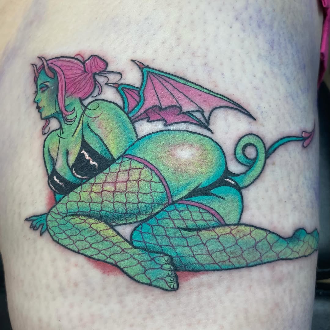Colorful mermaid tattoo on thigh featuring green scales, pink hair, bat wings, and black bikini top with turquoise outlines.