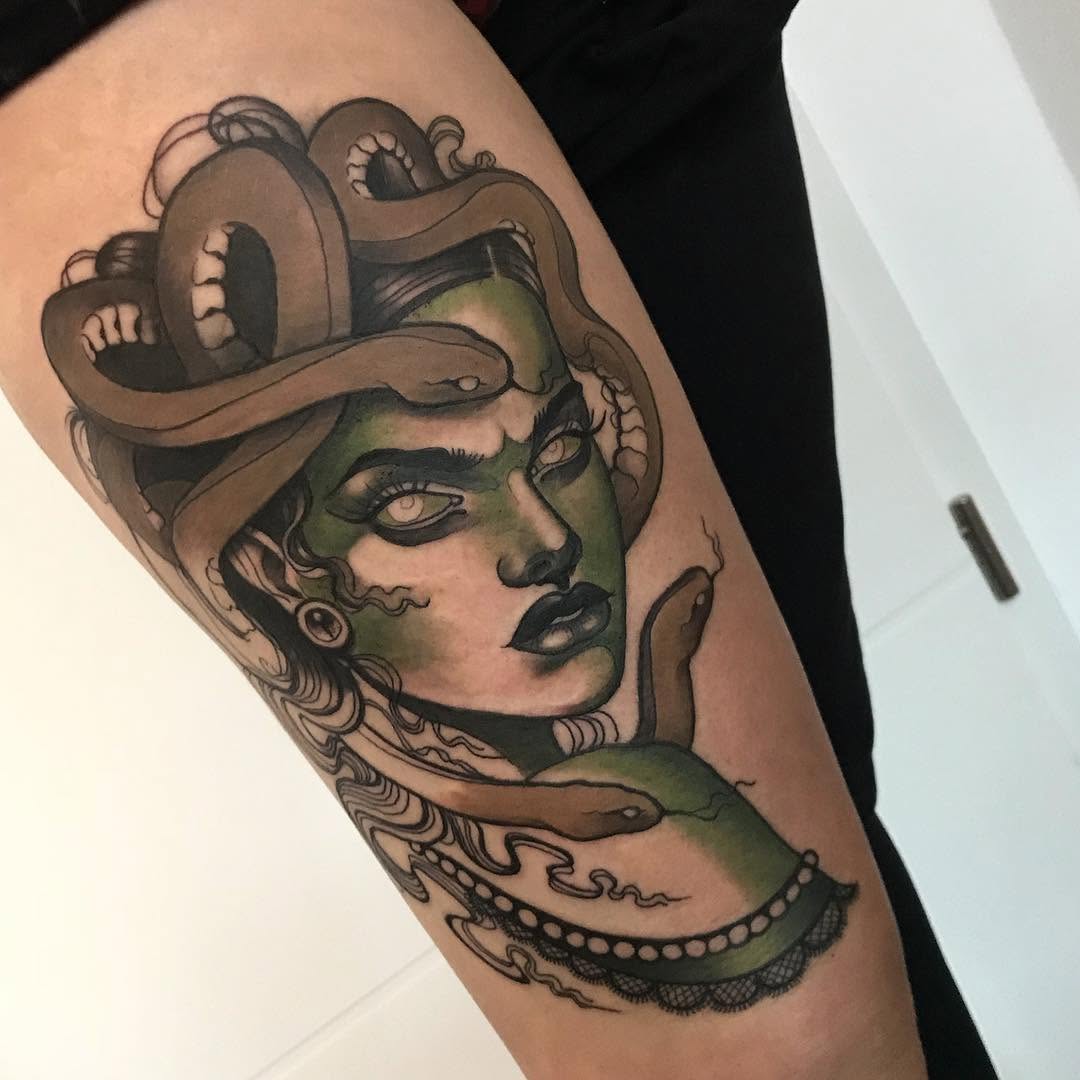 Medusa head tattoo on upper arm featuring green-toned skin, serpent hair, pearl necklace, and snakes wrapping around the neck and shoulder.
