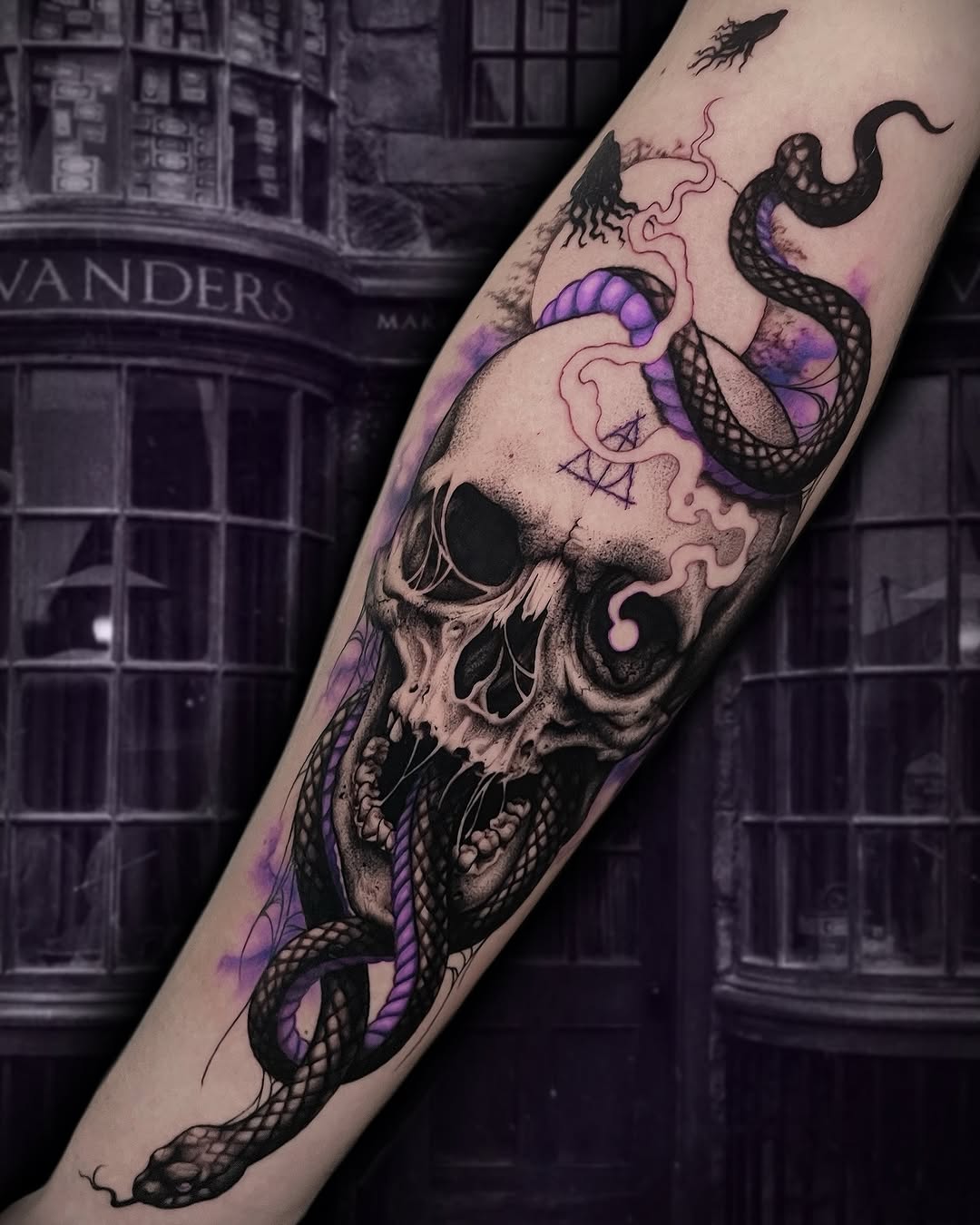 Skull with intertwined serpents and purple watercolor accents on a forearm, displayed against a dark architectural background.