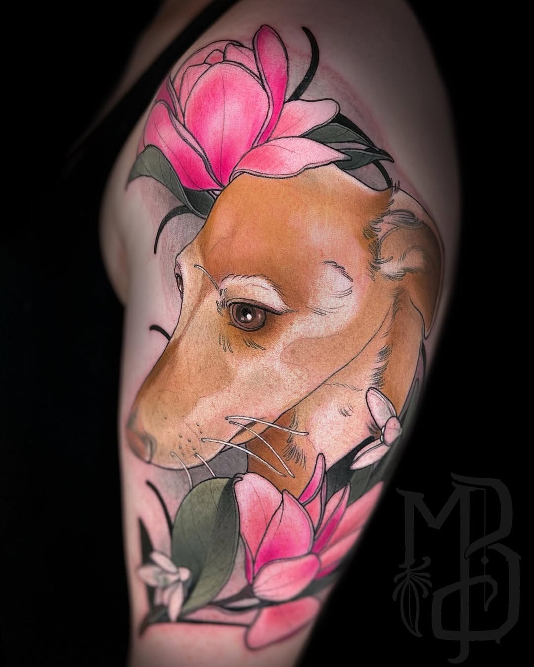 Colored shoulder tattoo featuring a brown cat's head with closed eyes surrounded by pink flowers and green leaves.
