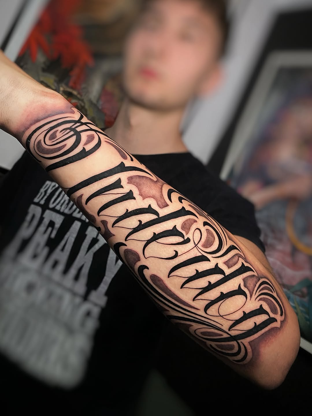 Large ornamental arm sleeve tattoo featuring black linework with red and brown shading, displaying swirling patterns and decorative elements wrapping around the forearm.