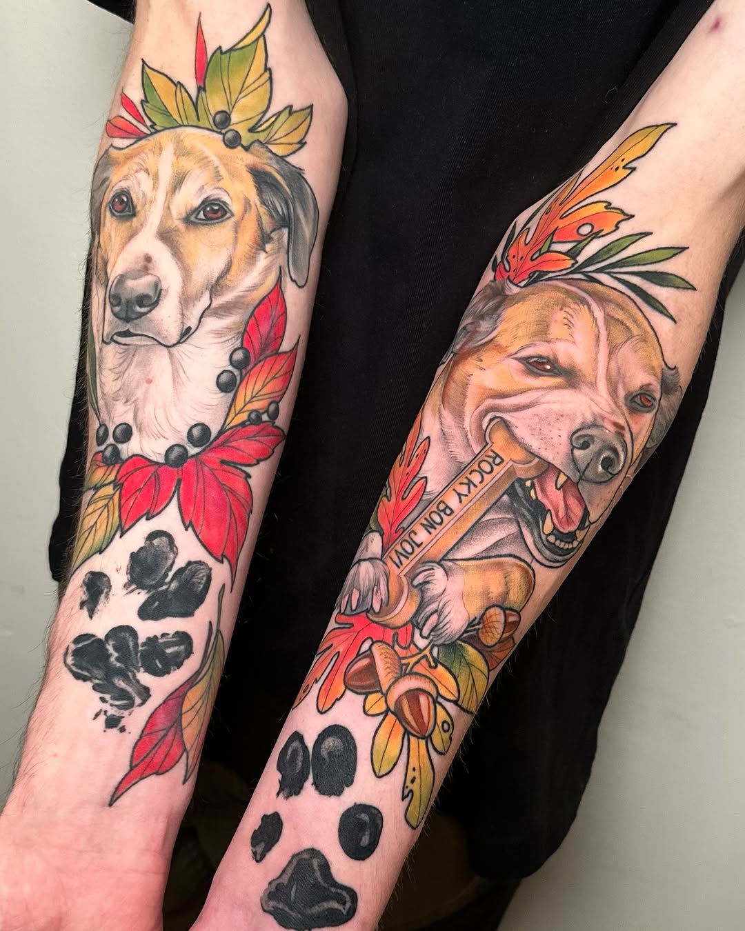 Two forearm tattoos featuring dog portraits with floral crowns and paw prints, accented with red and gold leaves and a banner with text.
