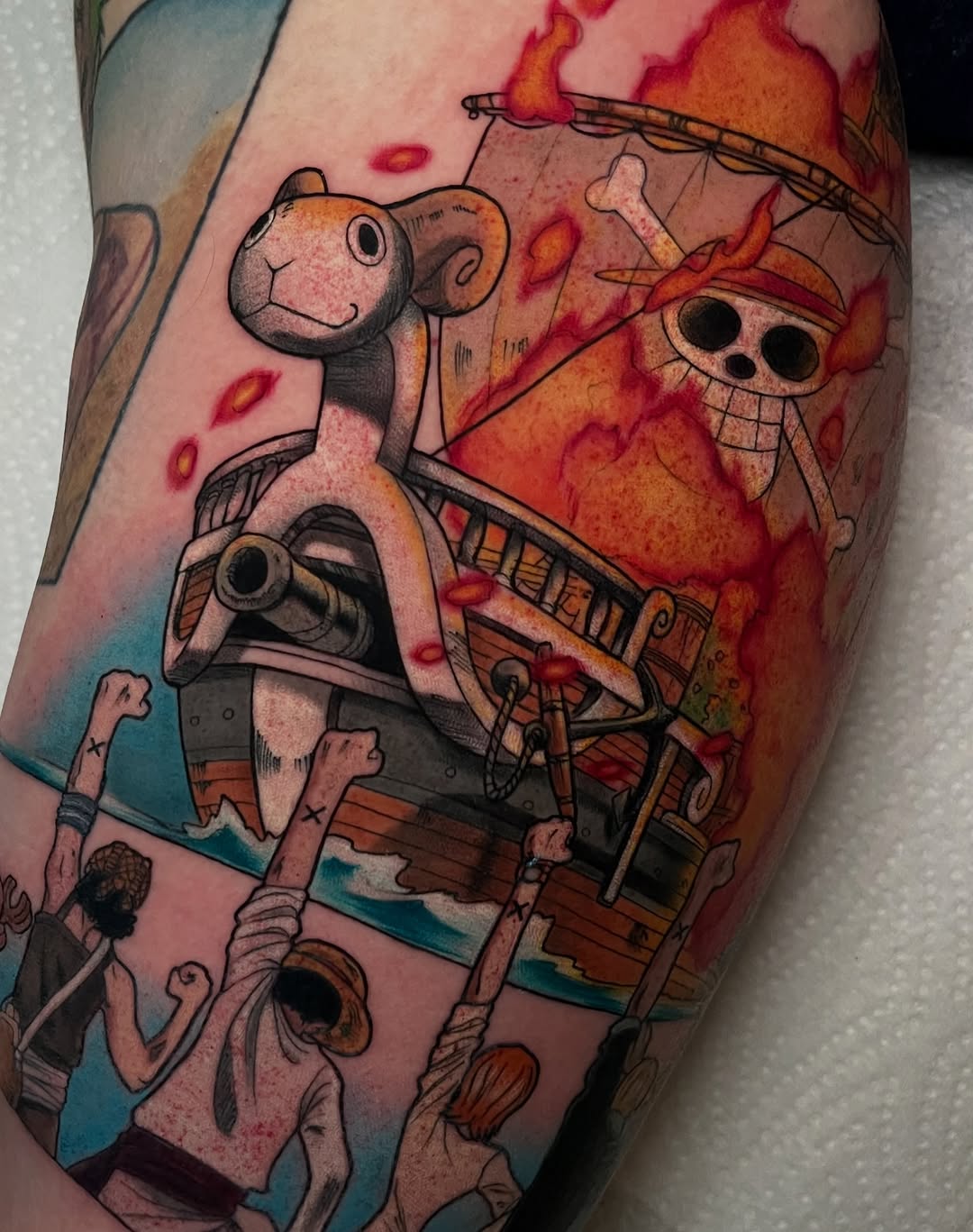 Colorful leg tattoo featuring skeletal characters with large eyes, a monkey figure, burning buildings, and flames in orange, red, teal, and pink tones.