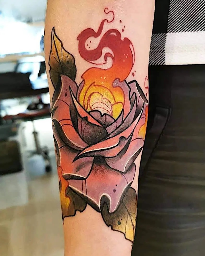 Colorful rose tattoo on forearm featuring red, orange, yellow, and black petals with green leaves and red flames rising from the bloom.