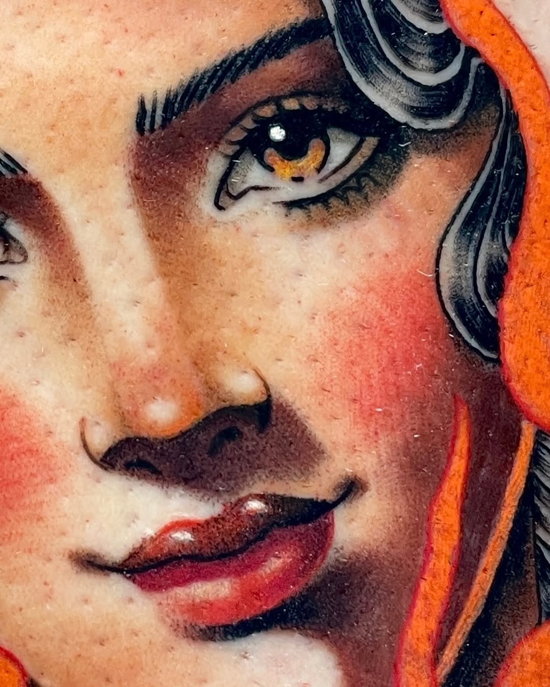 Detailed face tattoo on chest featuring a woman with golden eyes, dark hair, red lips, and orange flames, rendered in color.