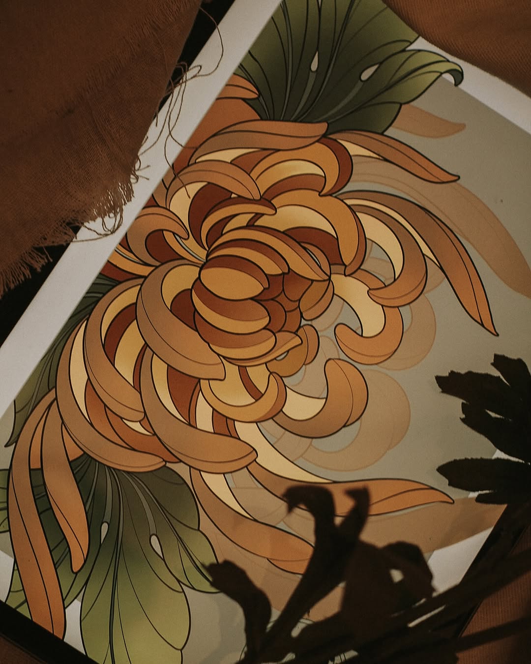 Chrysanthemum flower tattoo in warm orange and golden tones with green leaves on the upper arm, shown on brown skin.