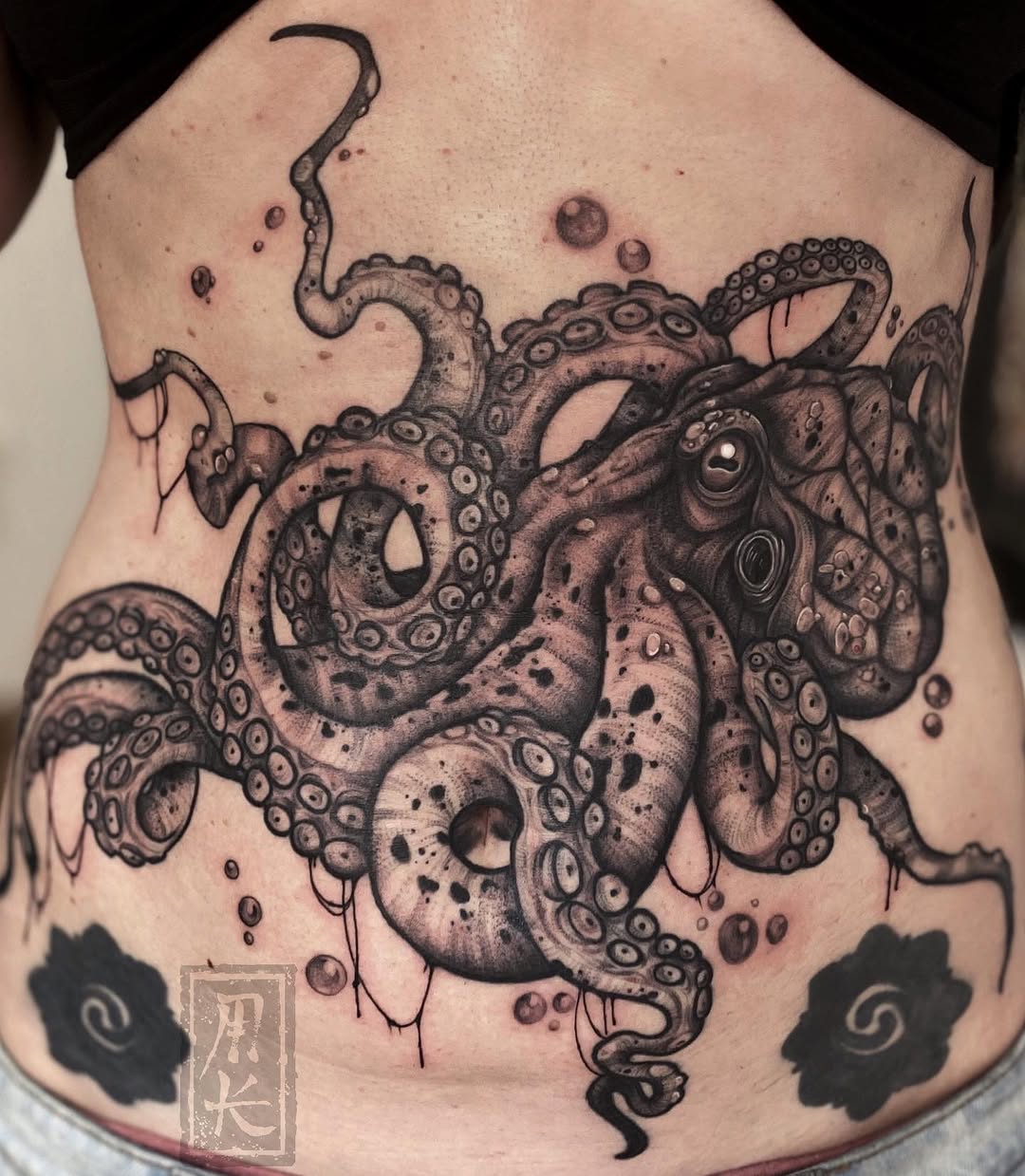 Octopus with detailed tentacles and suction cups on the chest and torso in black and grey ink, with decorative cloud elements on the sides.