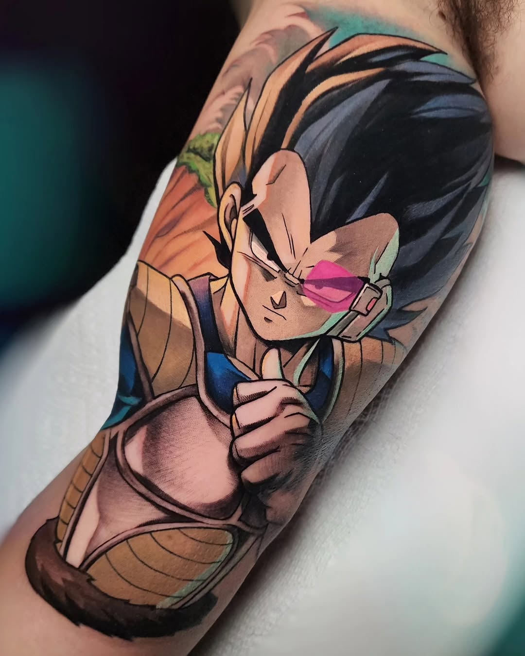 Colorful tattoo on an arm featuring a character with spiky hair, pink sunglasses, and brown outfit, rendered in vibrant oranges, blues, and teals.