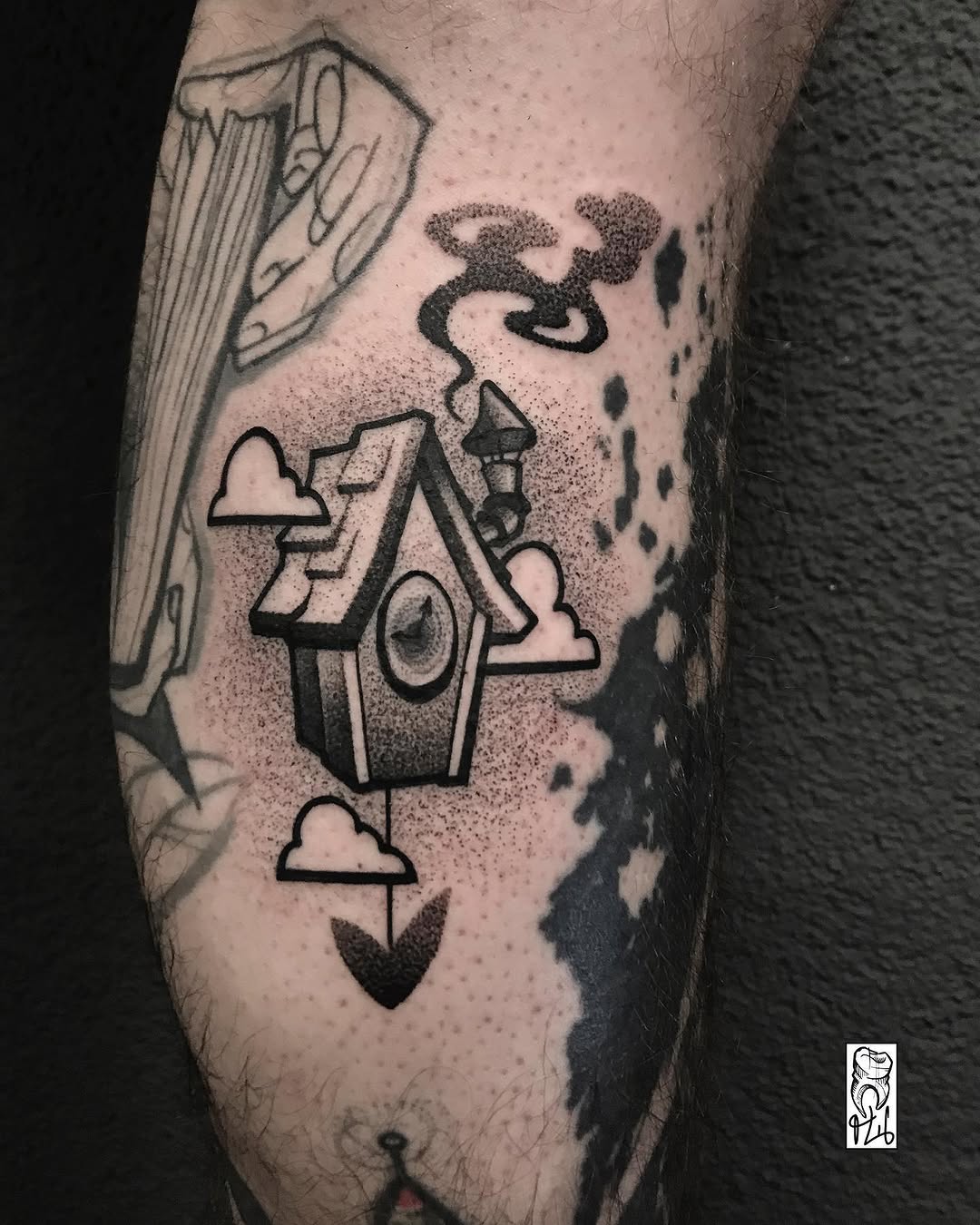 Tattoo on inner arm featuring a house with a tower, clouds, hearts, and abstract elements above in black ink with dotwork shading.