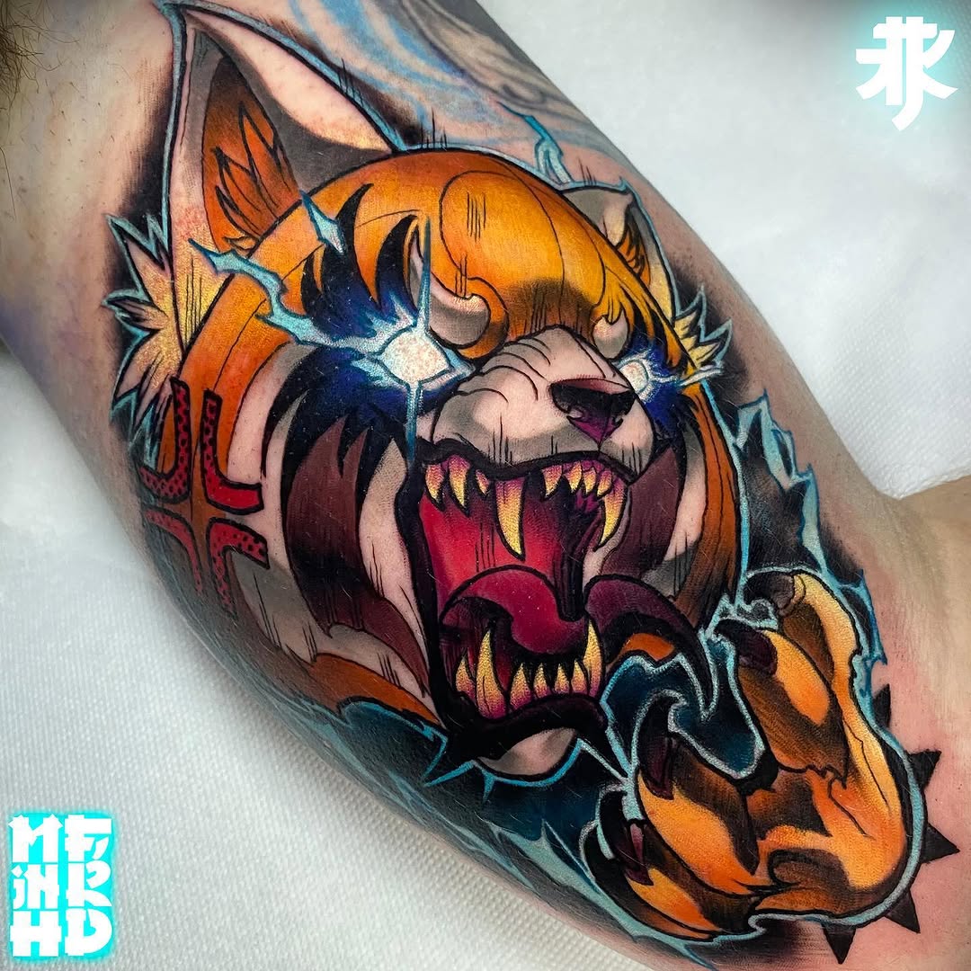 Colorful demon skull tattoo on upper arm featuring orange and blue tones with sharp teeth, spikes, and detailed shading.