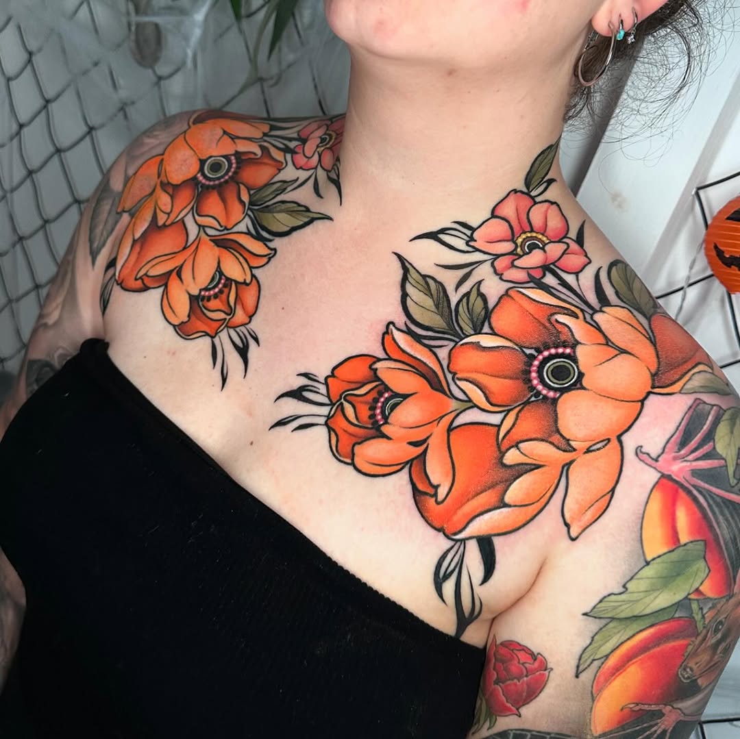 Colorful floral chest and shoulder tattoos featuring orange and red flowers with green leaves and black outlines on pale skin.