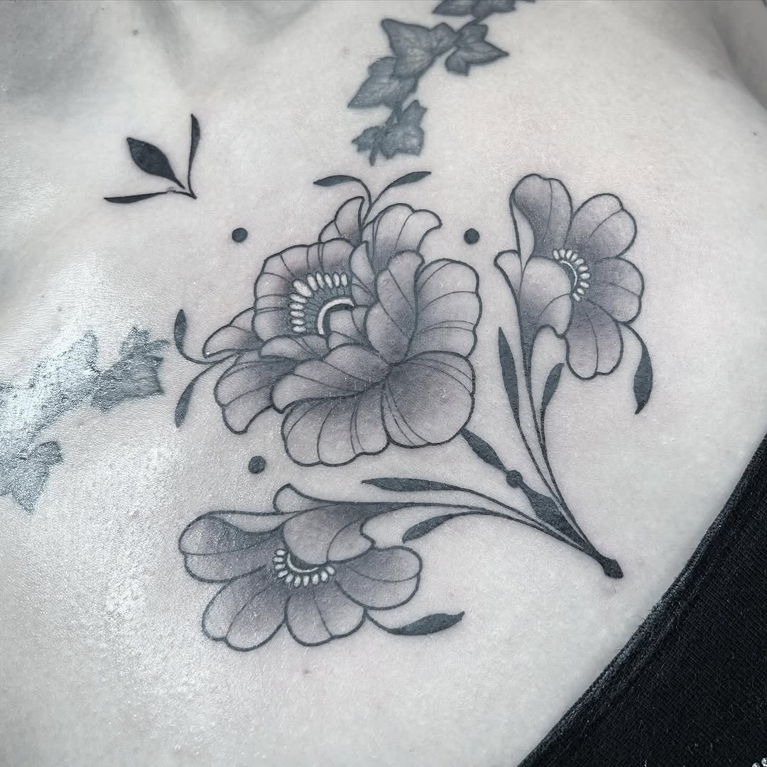 Delicate gray-inked floral tattoo on chest featuring three blooming flowers with detailed centers, leaves, and decorative dots.