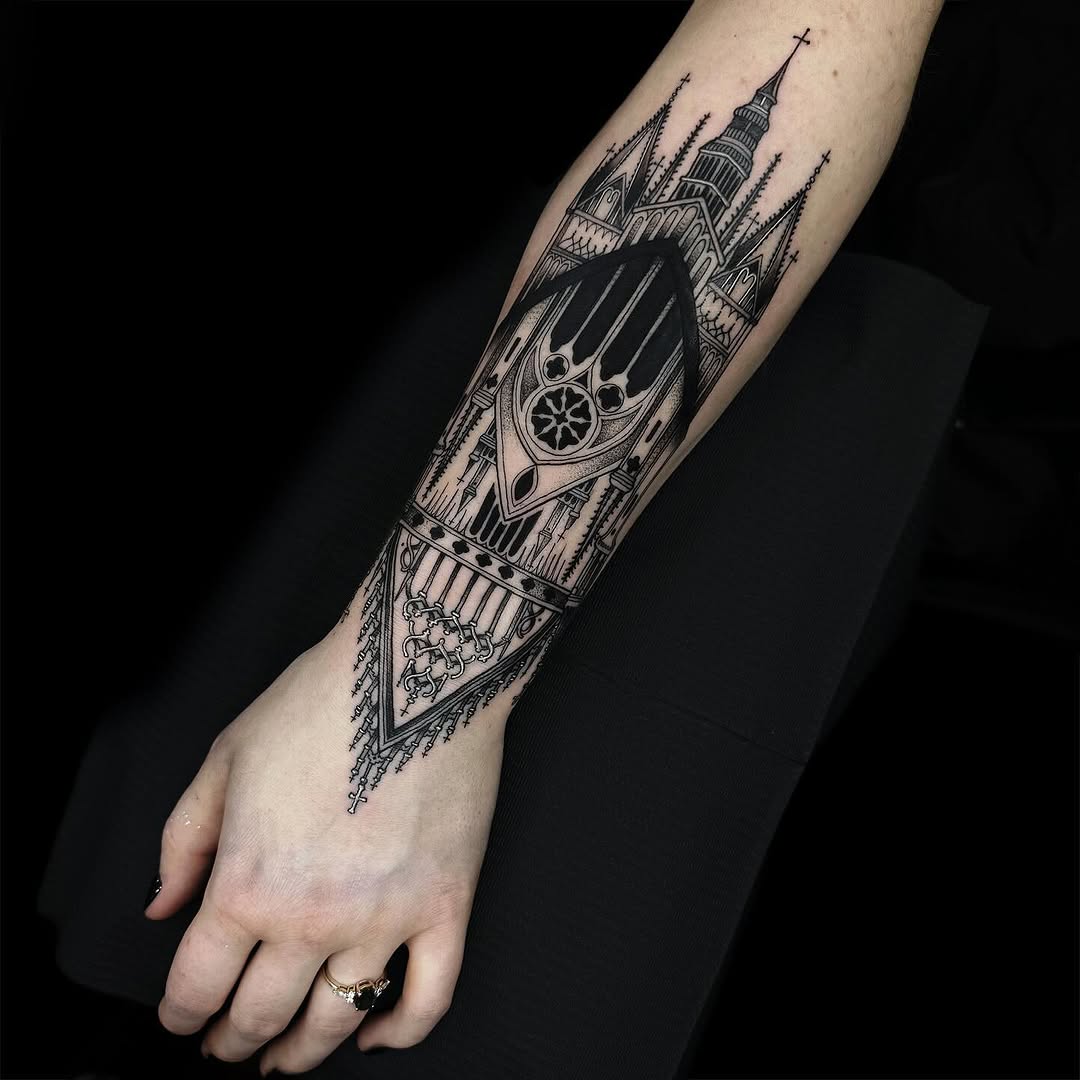 Detailed black ink tattoo on forearm featuring a ship with steering wheel, cathedral with spires, and ornamental geometric designs.