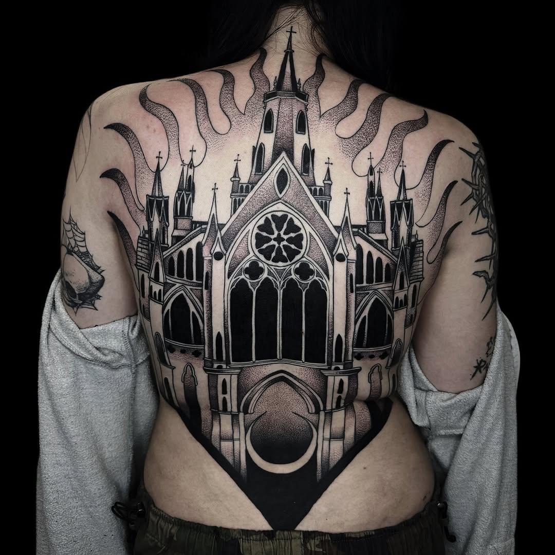 Back tattoo featuring a gothic cathedral with spires, crosses, tentacles, and a moon crescent in black ink on pale skin.