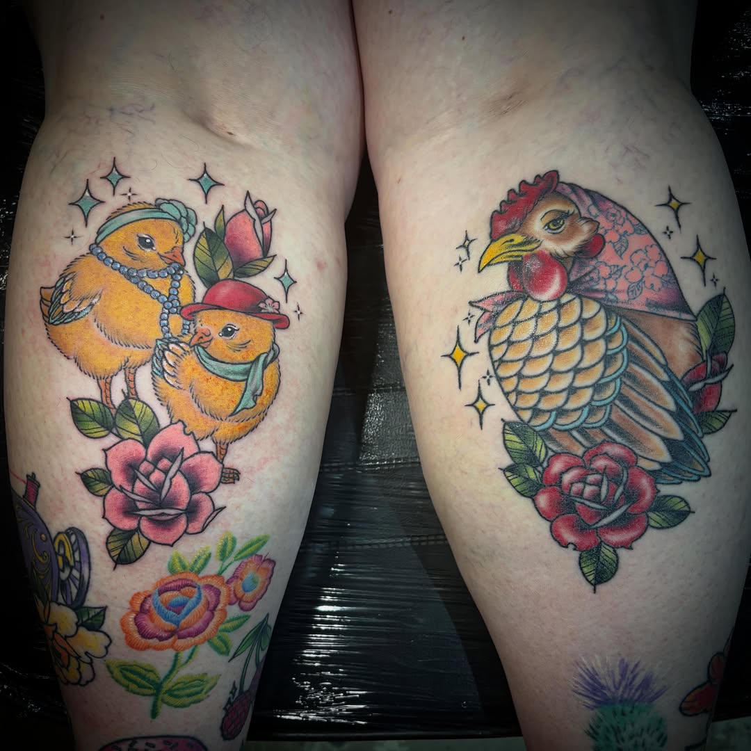 Two complementary leg tattoos featuring yellow chicks with pearls on the left and a red rooster with scaled feathers on the right, both surrounded by pink roses and sparkle stars.