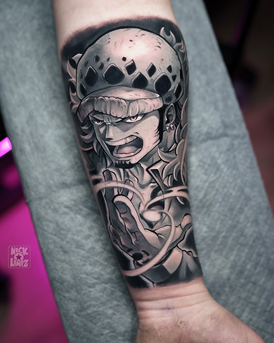 Detailed monochrome tattoo on a person's forearm featuring an expressive character wearing a spiked helmet, positioned vertically from elbow to wrist.