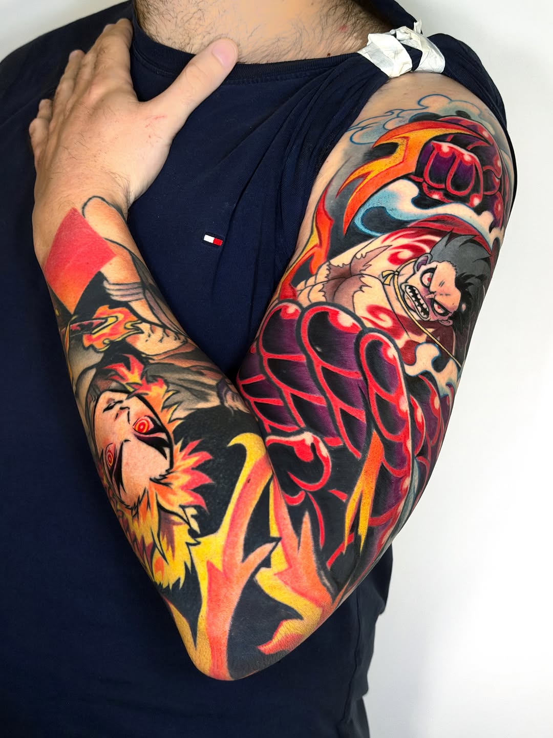 Colorful full-sleeve tattoo featuring a lion's head, human face, anatomical heart, and decorative elements in red, orange, yellow, and black ink on the arm.