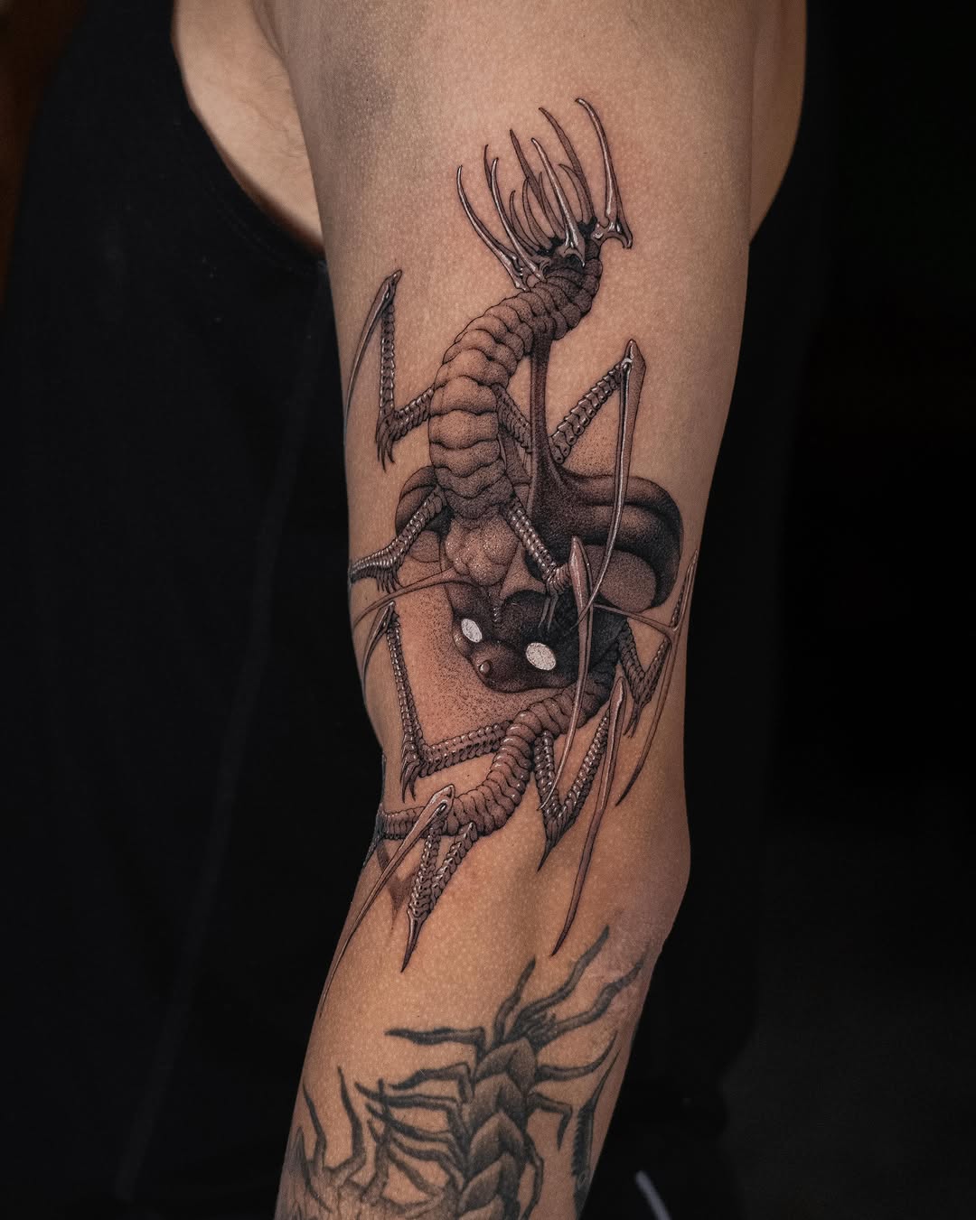 Detailed leg tattoo featuring a multi-armed alien creature with tentacles and claws, rendered in black ink on the thigh with additional smaller designs below.