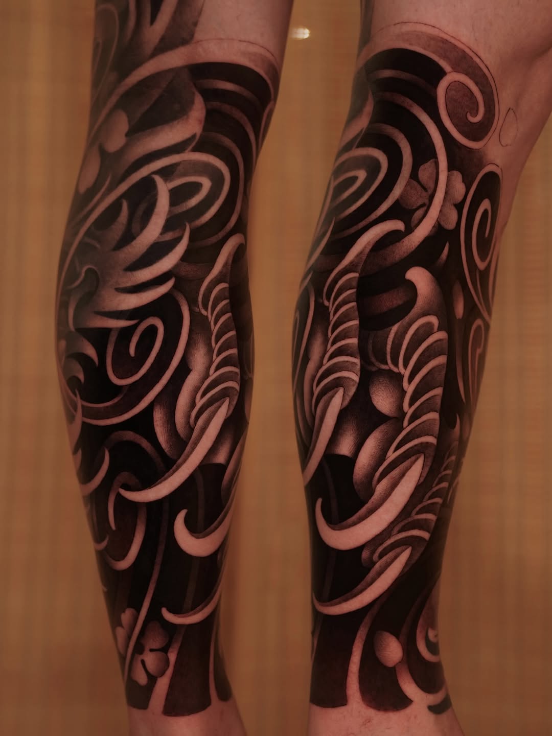 Pair of matching leg sleeves featuring ornate scrollwork and filigree patterns in shades of pink and brown with deep black shadows.