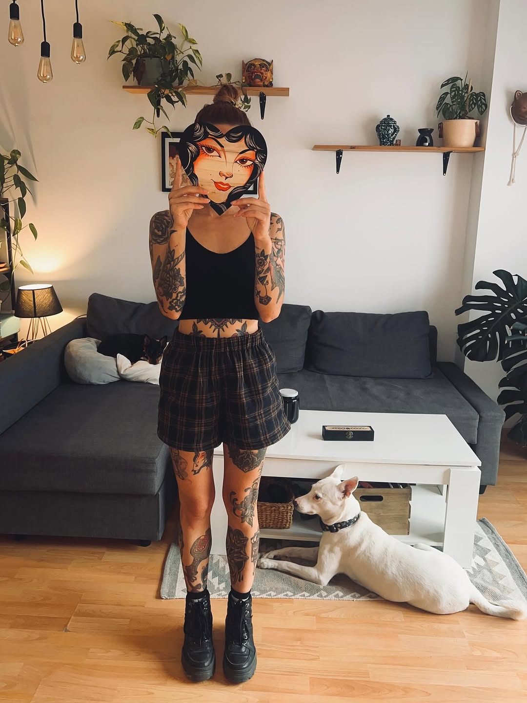 Full-body tattoo coverage featuring ornamental designs on arms and legs, displayed by a person wearing a black crop top and plaid shorts.